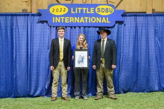 Grady Gullickson, Sadie Vander Wal and Cody Gifford stand in front of backdrop at Little "I".