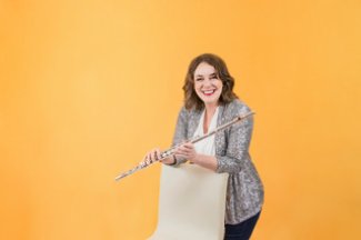 Elizabeth Robinson poses with her flute in front of a yellow background