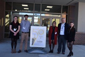 Geography club officers and SDSU advisors standing by the front entrance next to the 50th Convention sign.