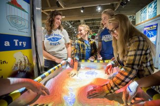 Four students interacting with the weather exhibit.