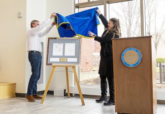 Craig Silvernagel, associate professor of entrepreneurship and innovation management in the Ness School of Management and Economics, and Barb Heller, lecturer and entrepreneurship coordinator, unveil the plaque that displays the patent for the “Konnector,” a connector device that promotes children’s building skills.
