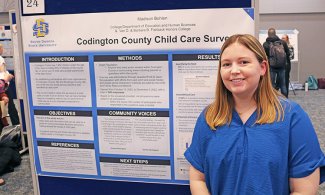 Madison Bohlen stands next to her top research poster in education and human development.