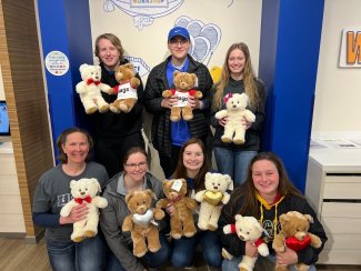 A group of seven chemistry club students holding up the bears they built at this Build-A-Bear event.