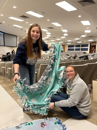 Two students from chemistry club showing off a tied fleece blanket.