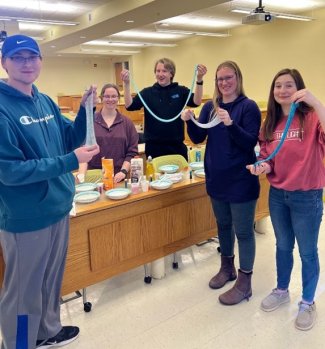 Five chemistry club students holding up their slime creations.