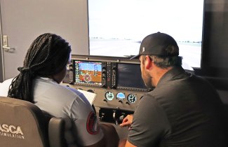 Aim High Flight Academy student Gabrielle Bernard-Ngujede trains with SDSU certified flight instructor Walker Risa on a flight simulator at the Brookings Regional Airport.