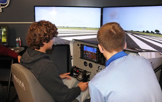 A Career and Technical Education Academy student from Sioux Falls uses a flight simulator with assistance from an SDSU aviation student during a site visit at the Brookings Regional Airport in October.