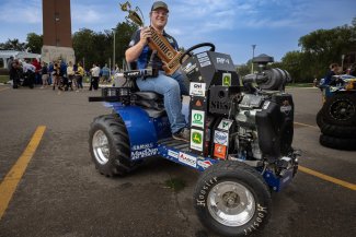 Mark Hague, an ag and biosystems engineering major, shows off the first-place trophy as he sits on a quarter scale tractor.