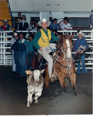 Craig Korkow, SDSU Rodeo Booster, is riding a horse while roping a calf.