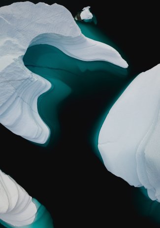 An overhead view of icebergs in the ocean showing the depth of the iceberg and their melting.