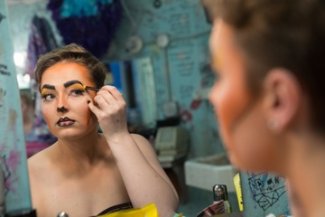 Student putting on makeup before theatre performance.