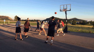 "Students play basketball at an outdoor hoop "