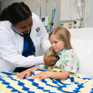 Female student listening to the heart of a pediatric patient.